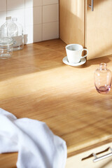 A sunny kitchen with white tile walls, a wooden table and sink.