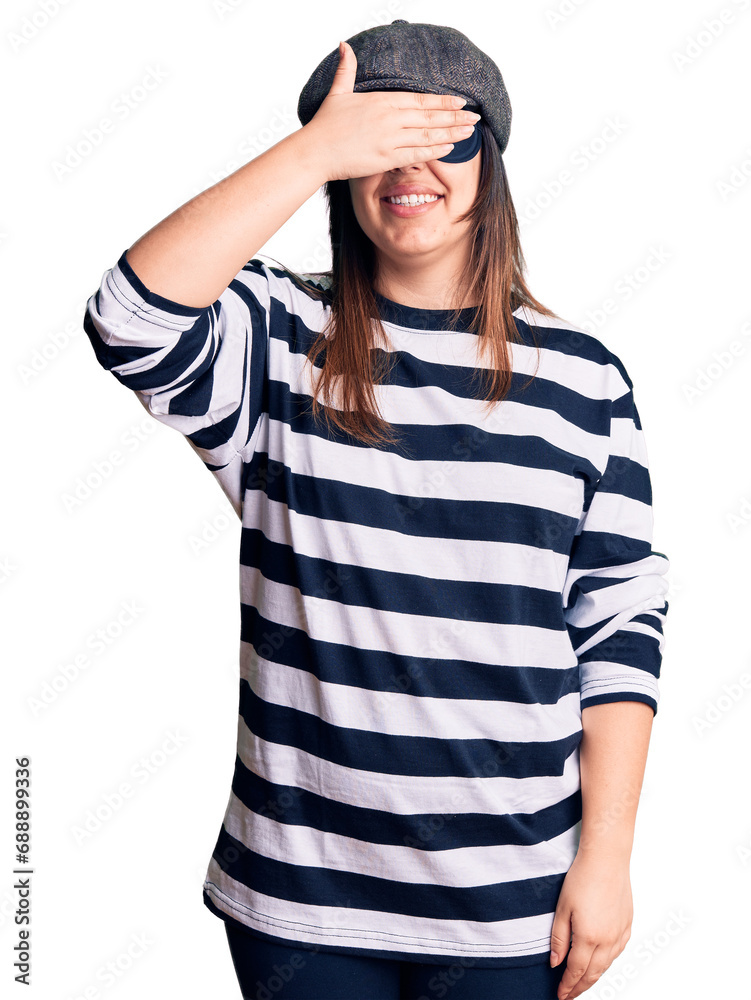 Sticker Young beautiful brunette woman wearing burglar mask smiling and laughing with hand on face covering eyes for surprise. blind concept.