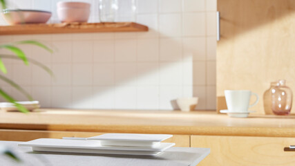 A sunny kitchen with white tile walls, a wooden table and sink.