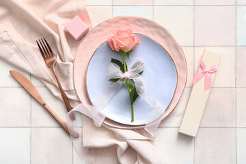 Beautiful table setting with gift and rose for Valentine's Day on white tile background