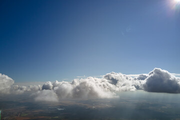 Aerial view from airplane window at high altitude of earth covered with white puffy cumulus clouds