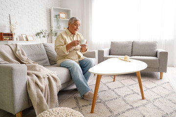Obraz premium Senior woman with cup of tea sitting on sofa at home