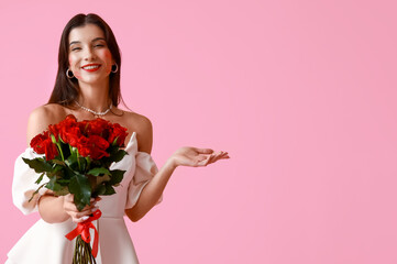 Happy young woman with kiss marks on her face and bouquet of roses on pink background