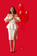 Beautiful young woman with heart shaped air balloons on red background