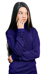 Young brunette girl with long hair wearing turtleneck sweater looking stressed and nervous with hands on mouth biting nails. anxiety problem.