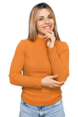 Young caucasian woman wearing casual clothes looking confident at the camera with smile with crossed arms and hand raised on chin. thinking positive.