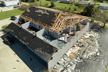 Wind destroyed house roof and walls with missing asphalt shingles after hurricane Ian in Florida....