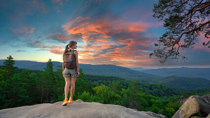 Young woman hiking alone on mountain footpath. Female hiker enjoying view of evening nature on...