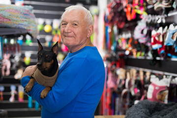 Portrait of mature man with his dog in winter clothes visiting pet supplies shop