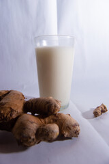 a glass of milk and ginger. photo studio with white background.