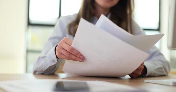 Woman company employee leafs through paper documentation