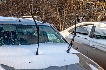 A snow-covered car in the parking lot on a winter day