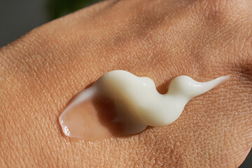 A smear of white moisturizer or sunscreen on a woman's hand.