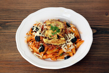 Grilled chicken pasta with black olive, cherry tomato, chili sauce and coriander served in dish isolated on table top view of arabic food