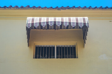 a classic house window with a Sunbrella canopy and iron grille