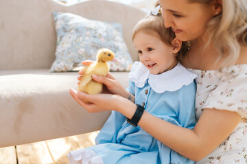 Closeup of elegance young mom and toddler adorable daughter in dress playing with little yellow...