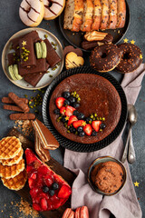 Tasty cake, cookies, waffles, macaroons, muffin. Delicious desserts on dark background. Food concept