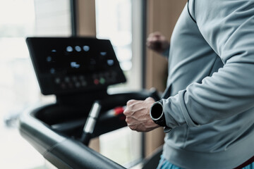 A man wearing smart watch and running on track treadmill, exercise fitness. Fitness, gym, workout...