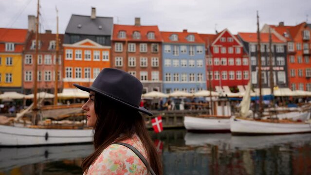 Portrait of woman with hat looking around happily in Nyhavn canal, Copenhagen