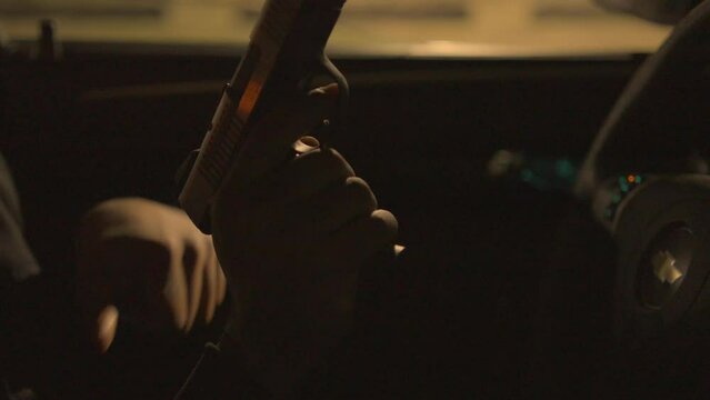 close up of a black man in the drivers seat of a car ejecting a bullet from his handgun
