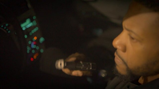 black man sitting in a car with a gun and an angry expression contemplating using the gun