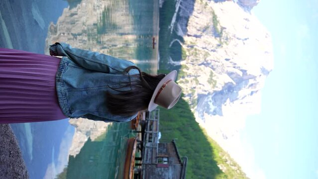 Woman enjoying Lago di Braies scenic view in Dolomites, Italy. Vertical, rear