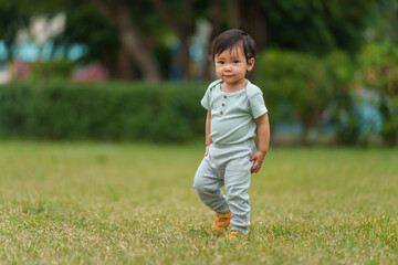 happy infant baby standing on green grass in park