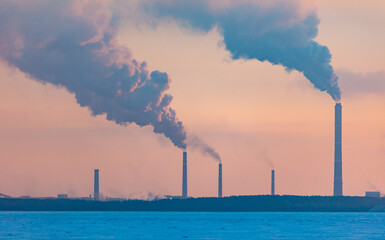 Smoke from the chimneys of an industrial plant at sunset in winter