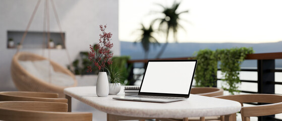A white-screen laptop computer on a table on a beautiful home balcony. Home workspace, closeup image