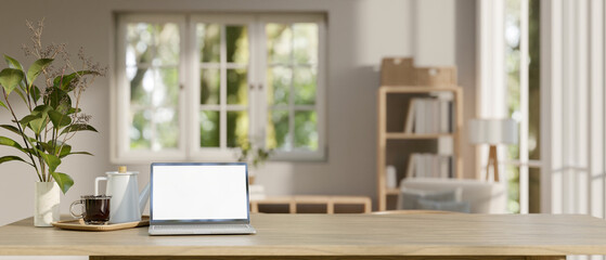 A white-screen laptop computer mockup on a wooden tabletop in a minimal Scandinavian living room.