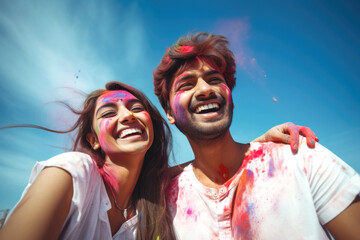 Obraz premium Loving couple of Indian ethnicity celebrating Holi festival with colours in a blue sky background 