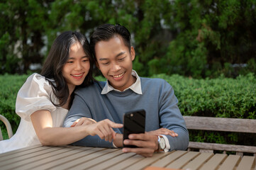 Cheerful lovely Asian couple spending time in the park, having good time together.