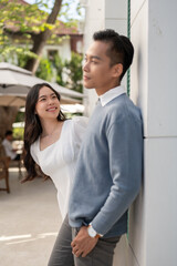 Young beautiful Asian couple standing in front of their house, having a good time together.