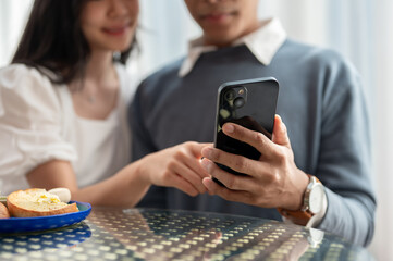 Close-up image of a lovely young Asian couple watching online videos on a smartphone together