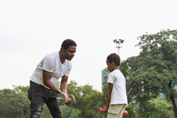Father and son playing and exercising with a dumbbell in park, Happiness family and Father's Day concepts