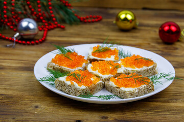 Canapes with red caviar and Christmas decorations on wooden table