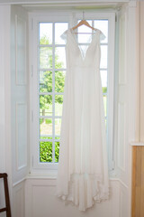 Robe de mariée suspendue devant une fenêtre