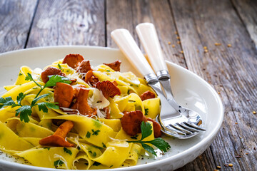 Pappardelle with chanterelle mushrooms on wooden table
