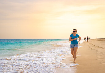 Fototapeta na wymiar Beautiful woman running on sunny beach Santa Maria, Sal Island, Cape Verde 