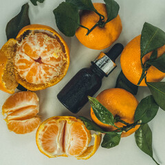Fragrant tangerine oil with tangerines on a white background. Bottles of citrus essential oil and sliced fruits on a white background. selective focus.
