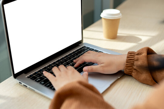 Close-up image of a woman using her laptop computer in a cafe. A white-screen laptop computer mockup