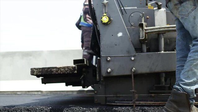 Compressing, compacting, leveling and smoothing the asphalt road surface using a Asphalt Paver Finisher. Process of asphalting road construction infrastructure