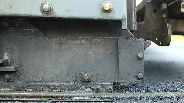 Compressing, compacting, leveling and smoothing the asphalt road surface using a Asphalt Paver Finisher. Process of asphalting road construction infrastructure