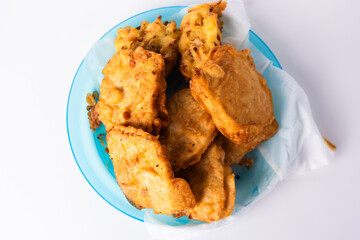 Flour fried tempeh on a blue plastic plate isolated on a white background