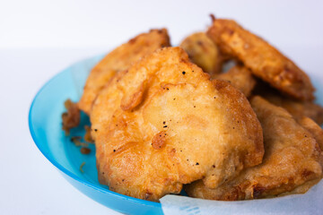 Flour fried tempeh on a blue plastic plate isolated on a white background