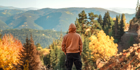 Rear view - Young tourist man standing on the hill against the mountains in autumn, Adventure, Travel