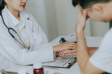Fototapeta premium An Asian female doctor gives a pep talk to a male patient inside the hospital.