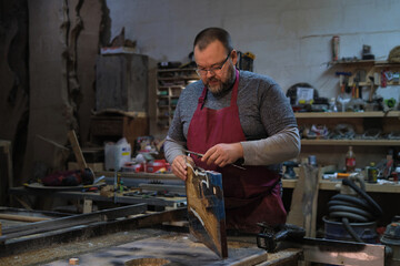 Man with planer on wood; meticulous and absorbed. Connects to the rising value of artisanal skills.