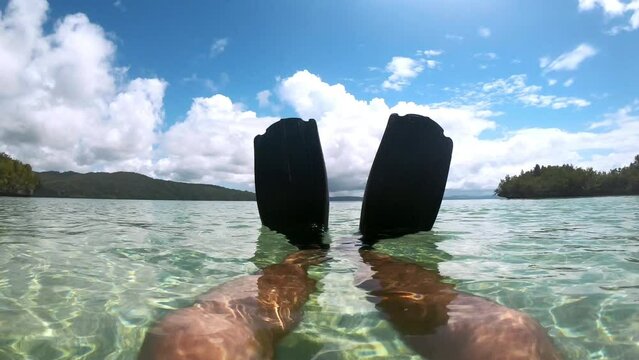 Legs, flippers and person swimming in sea, travel and tropical holiday, summer vacation or adventure. Floating fins, diver and closeup of ocean water, snorkler watersport or tourist outdoor in nature