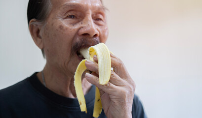 Just a healthy diet. Senior man eating banana at home. Breakfast or lunch time, healthy eating...